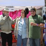 Three people standing outside a festival booth.