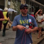 Man with blue shirt holding a beer can.