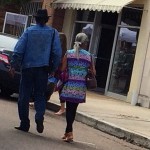 A man and woman walking in front of a store.