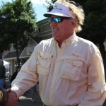 Man in white shirt and sunglasses smiles.