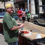 Man eating crawfish outdoors near building.