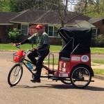 Man riding a red bicycle rickshaw.