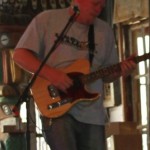 Man playing guitar in a dimly lit room.