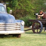 Blue vintage truck parked in grass with a man.