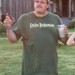 Man wearing green shirt holding a glass of milk.