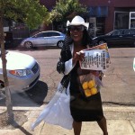 Woman in white holds lemons and flyers.