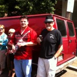 Four people standing by a red van.