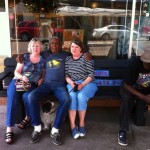 Four people sitting on a bench with a dog.