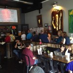 People gathered in a restaurant with a large painting.