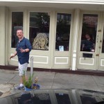 Man in blue shirt standing in front of store.