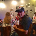 Man in black shirt sitting with friends.