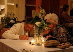 Two people sit at a table with flowers.