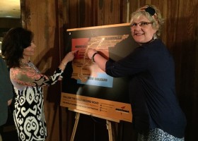 Two women pointing at a map of the American South.