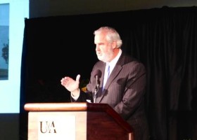 Man speaking at podium with microphone.