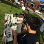 Artist drawing portraits at outdoor market.