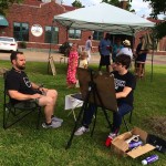 Two men sitting outside, painting and relaxing.