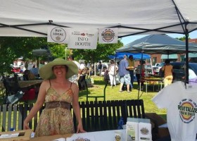 Woman at farmers market info booth.