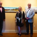 Three people stand in front of artwork.