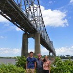 Family posing under bridge on a sunny day.