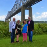 Four people standing by a bridge.