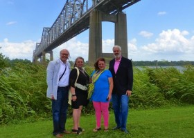 Four people standing by a bridge.