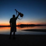 Silhouette of a man holding a guitar.