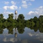 Water tower reflected in lake with trees.