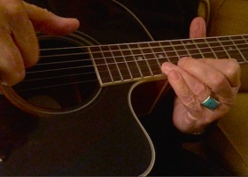 Person playing an acoustic guitar.