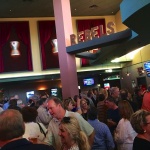 Crowd of people at a bar with a "Rebels" sign.