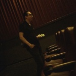 Man in a dark theater with rows of seats.