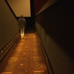 Woman walking down a carpeted hallway.