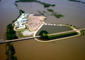 Flooded building complex with a road bridge.