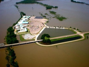 Flooded building complex with a road bridge.