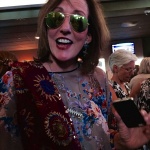 Woman wearing sunglasses and floral dress.