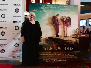 Woman stands with "Walk in the Woods" poster.