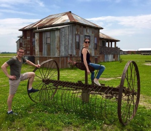 Couple posing with antique farm equipment.