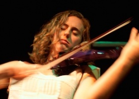 Woman playing an electric violin on stage.