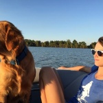 Woman in sunglasses with a golden retriever on a boat.