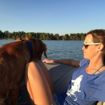 Woman in sunglasses with a dog on a boat.