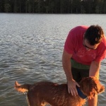 Man petting golden retriever in water.