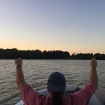 A man in a boat raising his hands in the air.