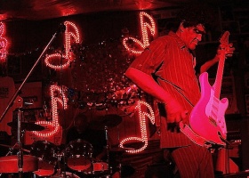 Man playing electric guitar in red light.