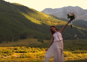 Woman holding flowers in mountain meadow.