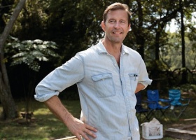 Man in a blue shirt smiling outdoors.