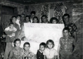 Family gathered around a white casket.