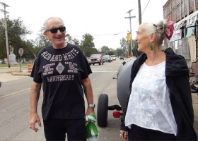 Two people talking in front of a truck.