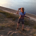 A woman takes a picture by the river.