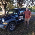 Man standing by blue SUV with logo.