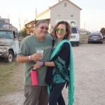 Couple smiling with drinks near an old truck.