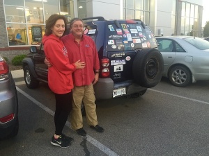 Couple posing by a sticker-covered Jeep.